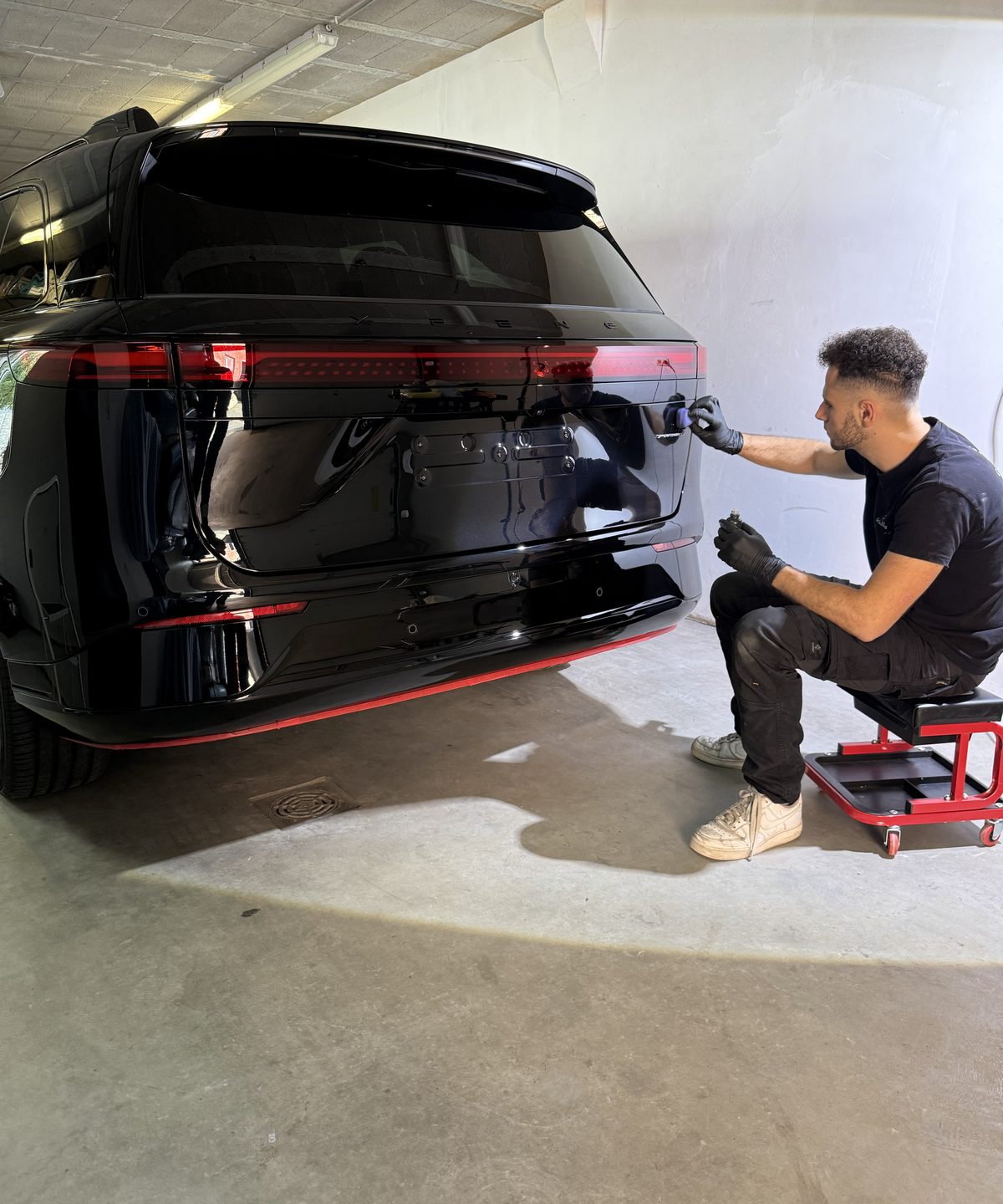 Detailer brengt keramische coating aan op de achterzijde van een zwarte Range Rover